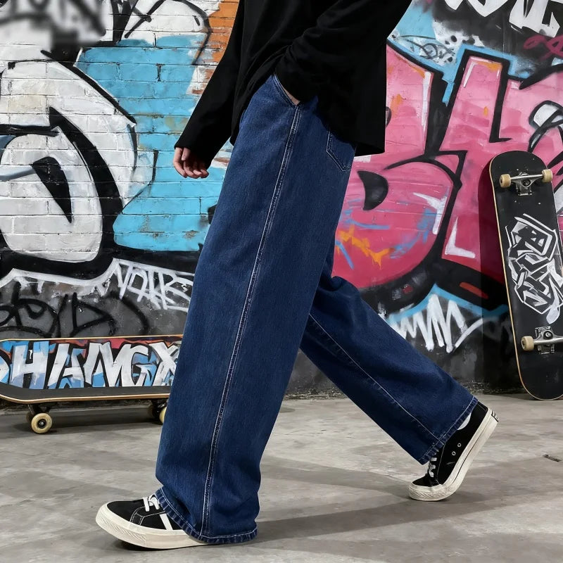 Person wearing blue jeans and black sneakers standing in front of a graffiti-covered wall with skateboards.