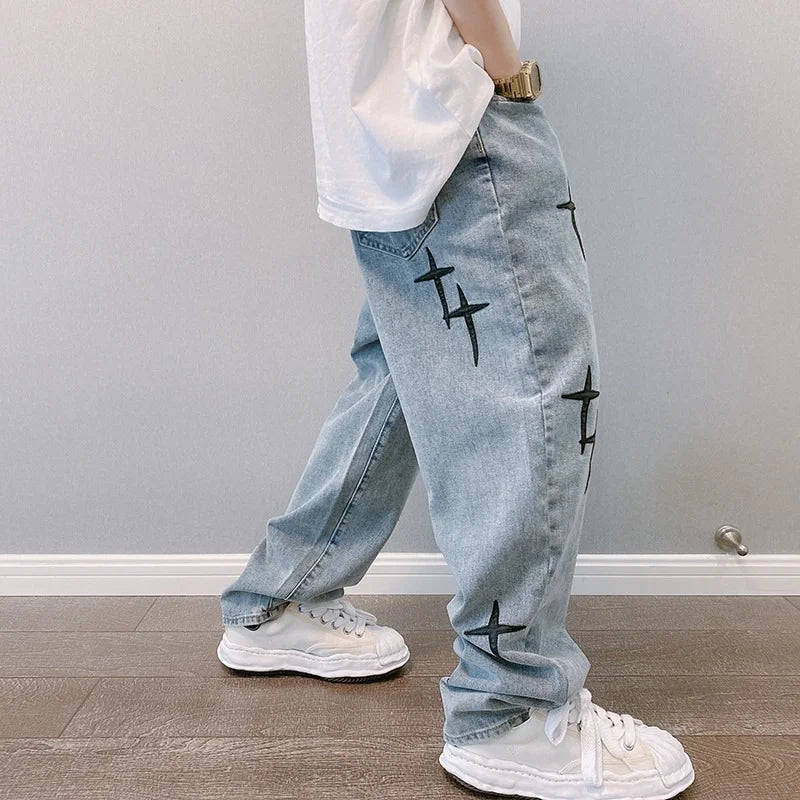 Light blue jeans with black star designs worn by a person on a plain background