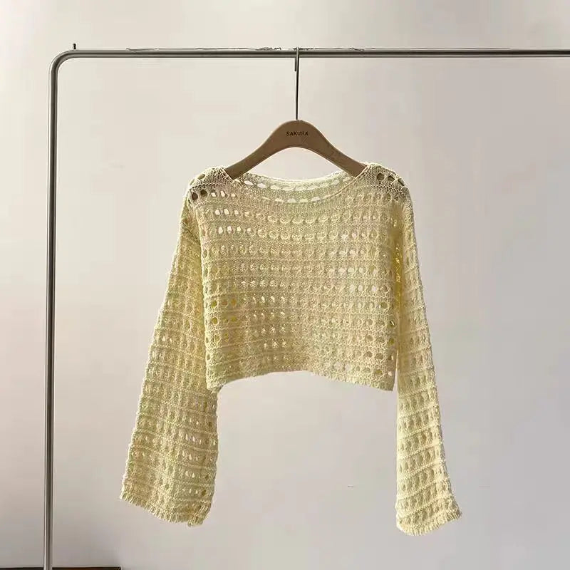 Yellow crochet sweater on a hanger against a plain background