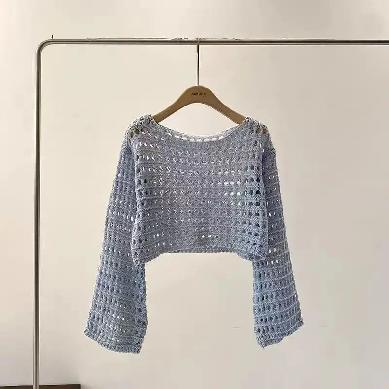 Crocheted sweater on a hanger against a plain background