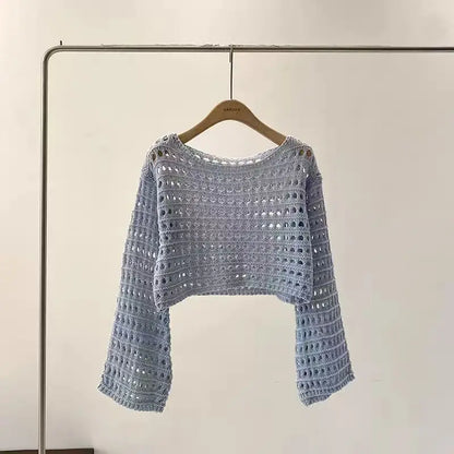 Crocheted sweater on a hanger against a plain background