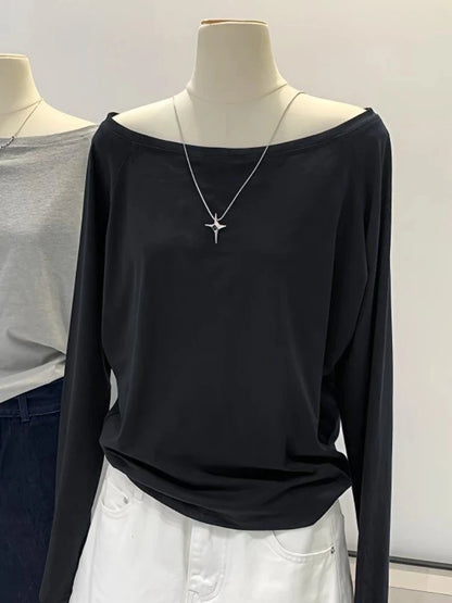 Black long-sleeve top on a mannequin with a necklace, against a neutral background
