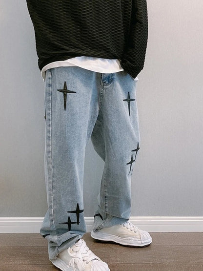 Person wearing light blue jeans with black star patterns and white sneakers against a plain background