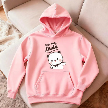 Pink hoodie with cartoon design and text on a light-colored surface