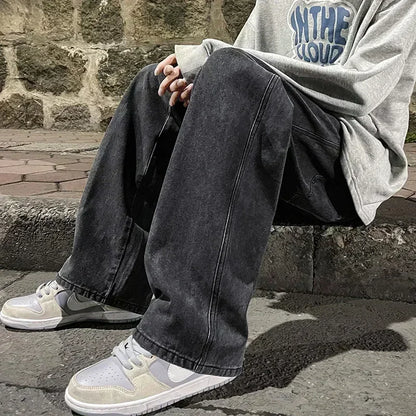 Person wearing a gray hoodie and dark jeans sitting on a stone ledge.