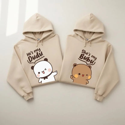 Two beige hoodies with cartoon characters and text on a light gray background