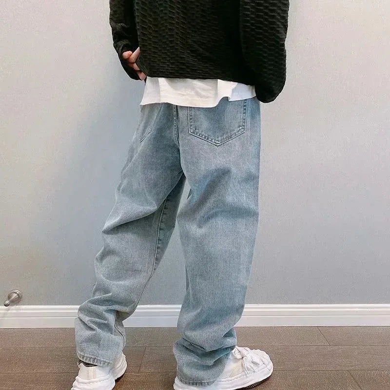 Person wearing light blue jeans and a black sweater against a plain background
