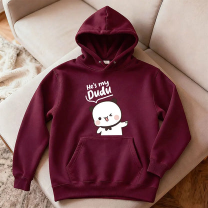 Maroon hoodie with cartoon character and text on a beige couch