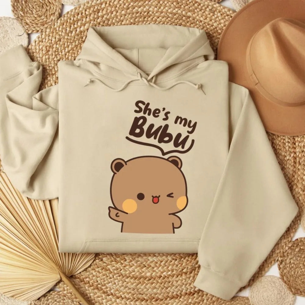 Beige hoodie with bear graphic and text 'She's my Bubu' on a woven surface.