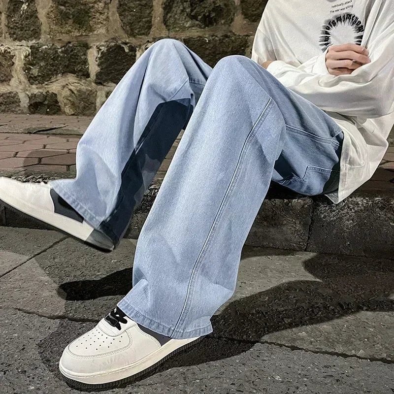 Person wearing light blue jeans and white sneakers sitting on a stone ledge.