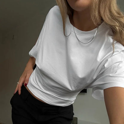 Person wearing a white t-shirt and black pants against a neutral background