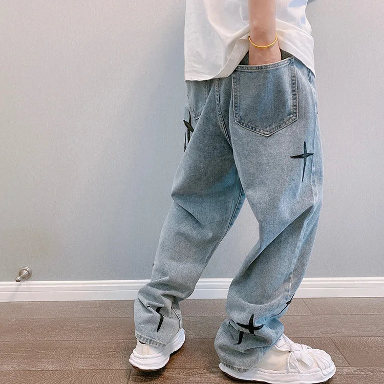 Light blue jeans with black airplane designs worn by a person against a plain background