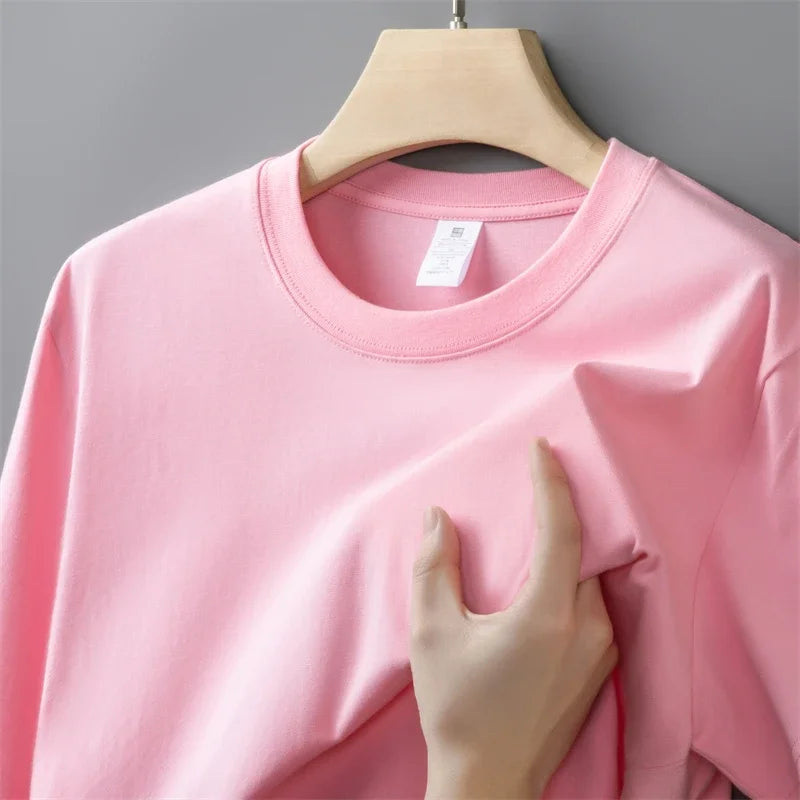 Pink sweatshirt on a hanger with a hand touching the fabric against a gray background
