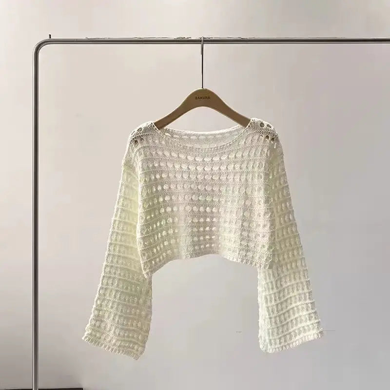 White textured sweater on a hanger against a plain background