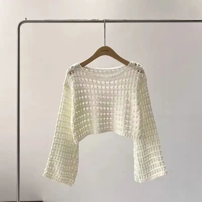 White textured sweater on a hanger against a plain background