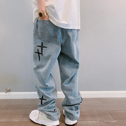Light blue jeans with black designs worn by a person against a plain background