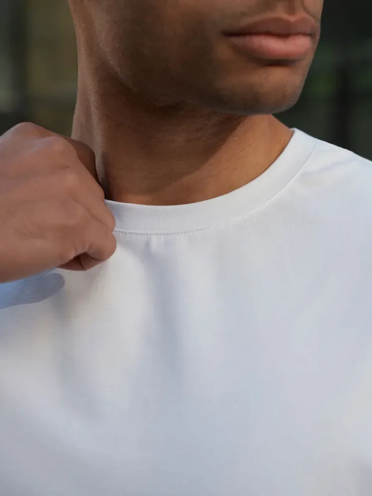 Person wearing a plain white t-shirt with a blurred background