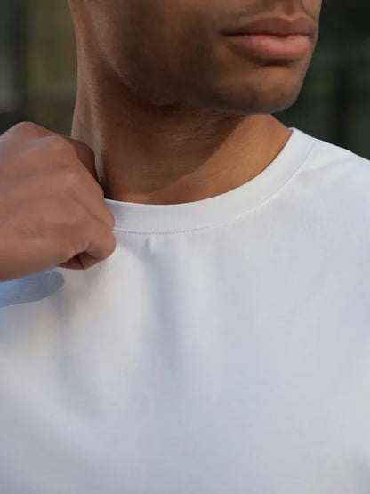Person wearing a plain white t-shirt with a blurred background