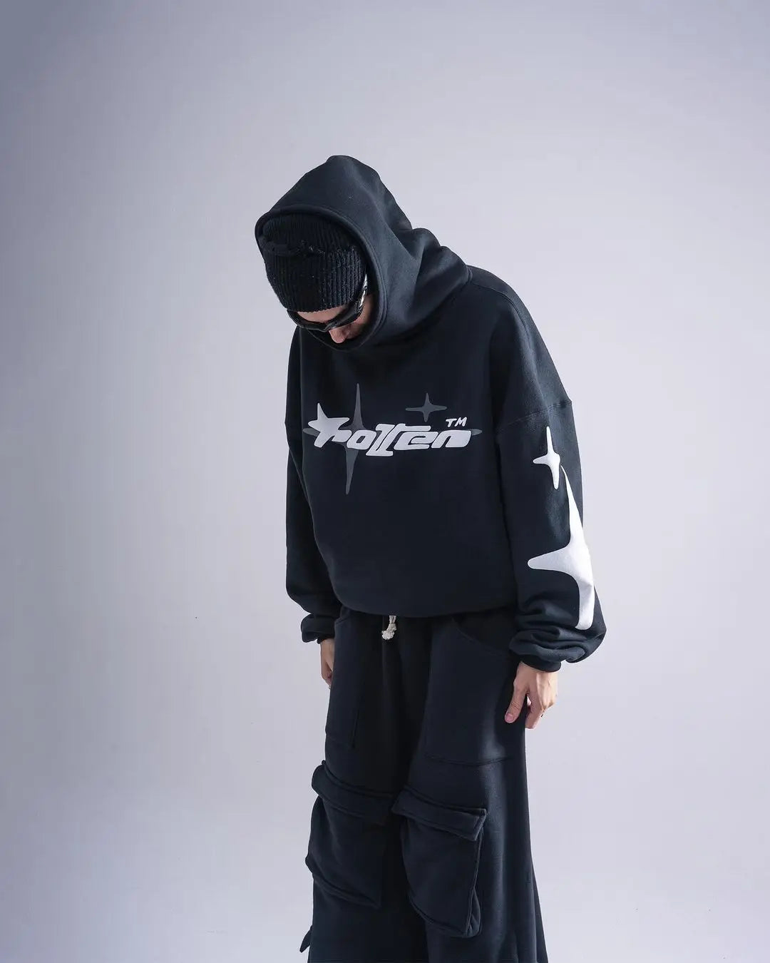 Person wearing a black hoodie with a logo on a gray background