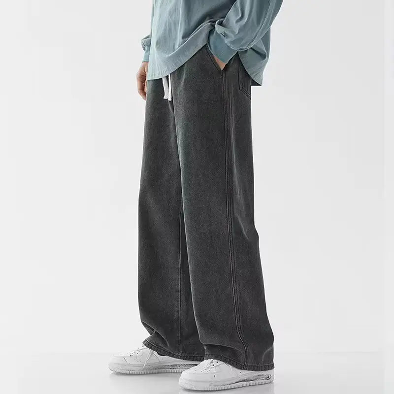 Person wearing dark gray wide-leg jeans and a light blue shirt on a white background