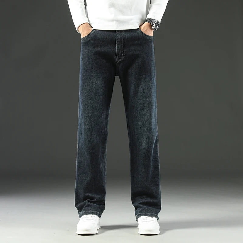 Person wearing dark blue jeans and white shoes on a gray background