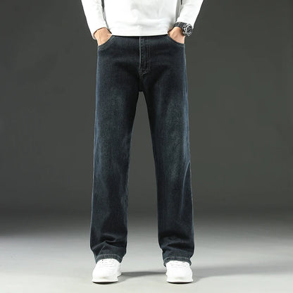 Person wearing dark blue jeans and white shoes on a gray background