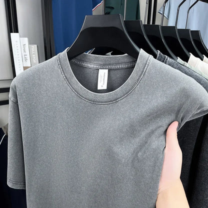 Gray t-shirt on a hanger with a hand holding it, in front of a mirror reflection.