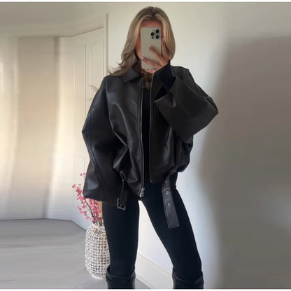 Person wearing a black leather jacket taking a mirror selfie.