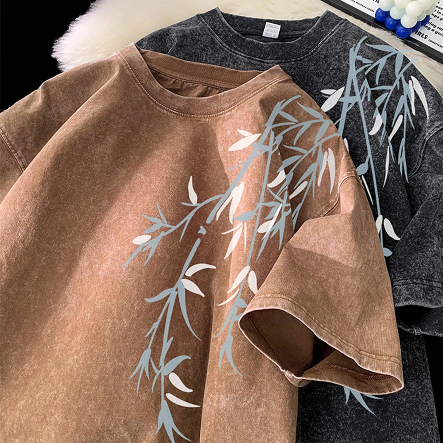 Brown and gray t-shirts with leaf patterns on a black background
