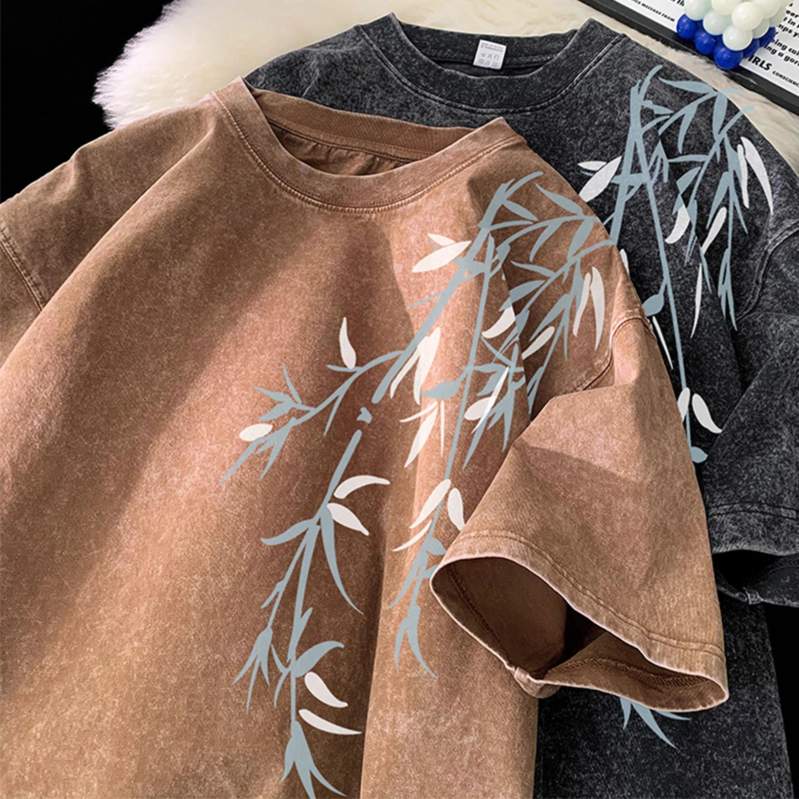 Brown and gray t-shirts with leaf patterns on a black background