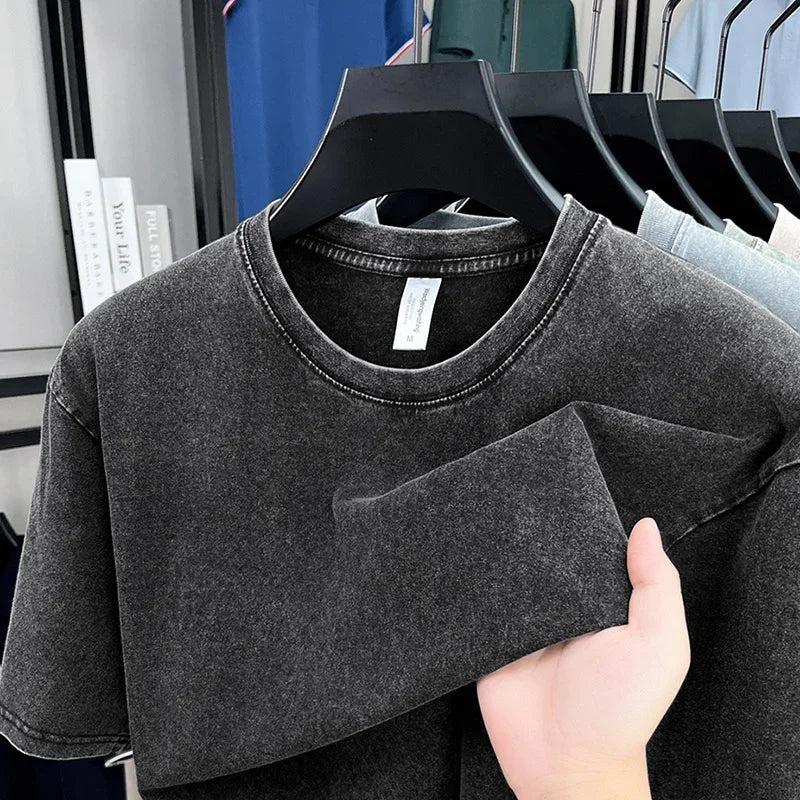Gray t-shirt held by a hand with a blurred store background