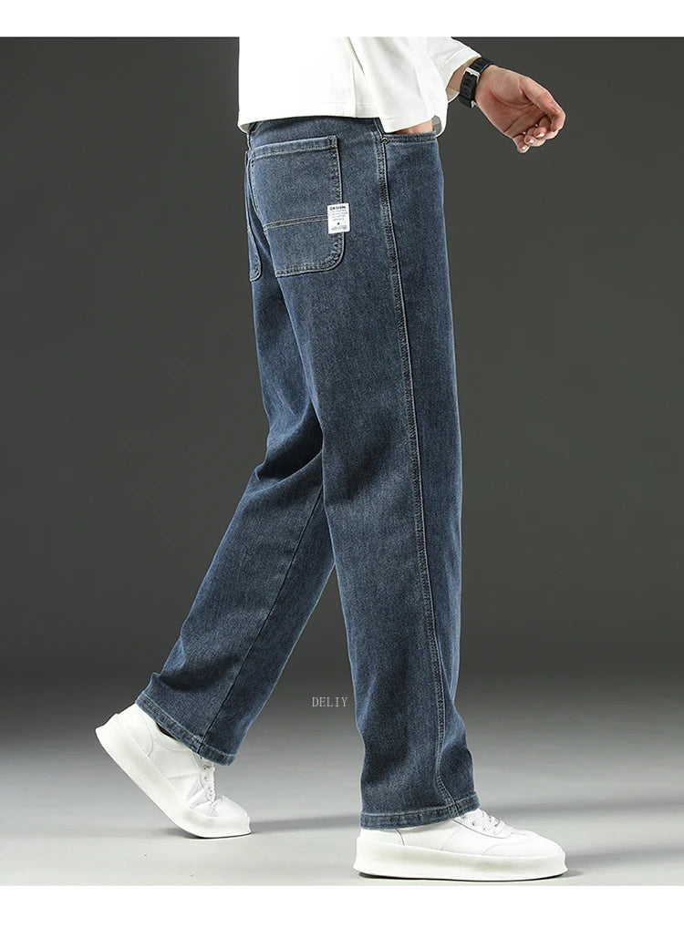 Person wearing blue jeans and white sneakers on a gray background