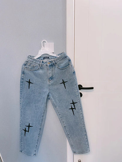 Light blue jeans with black cross designs on a white door.