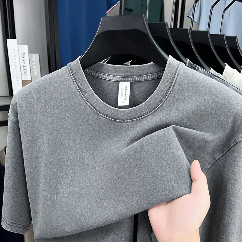 Gray t-shirt being held on a hanger with a blurred indoor background