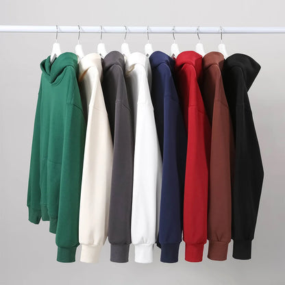Row of colorful hoodies on hangers against a plain background