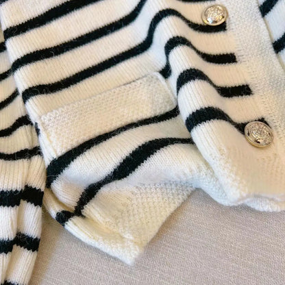 Close-up of a black and white striped cardigan with buttons on a beige surface
