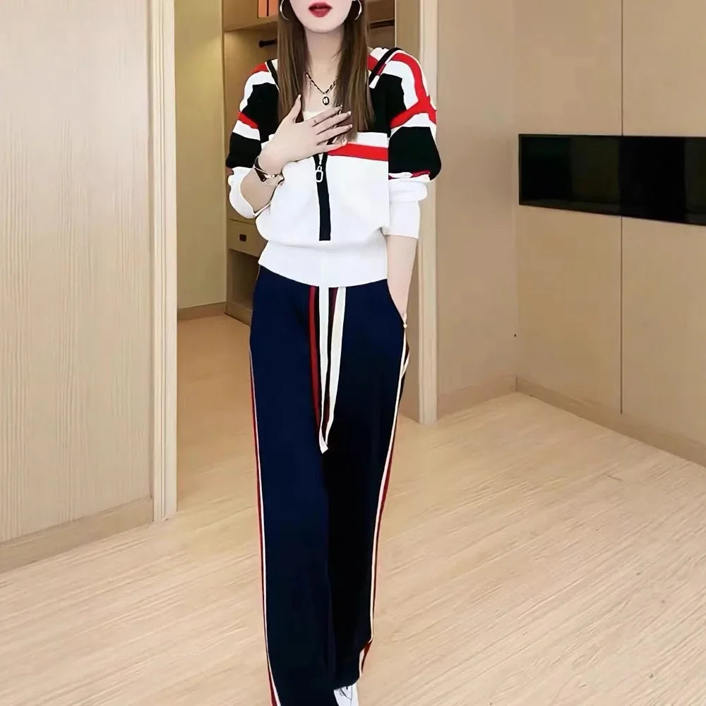 Woman wearing a colorful tracksuit in a room with wooden flooring and a black shelf.