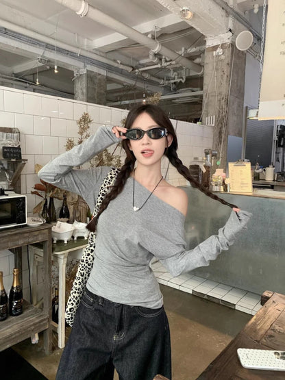 Woman posing in a casual setting with sunglasses, wearing a gray top and black pants.