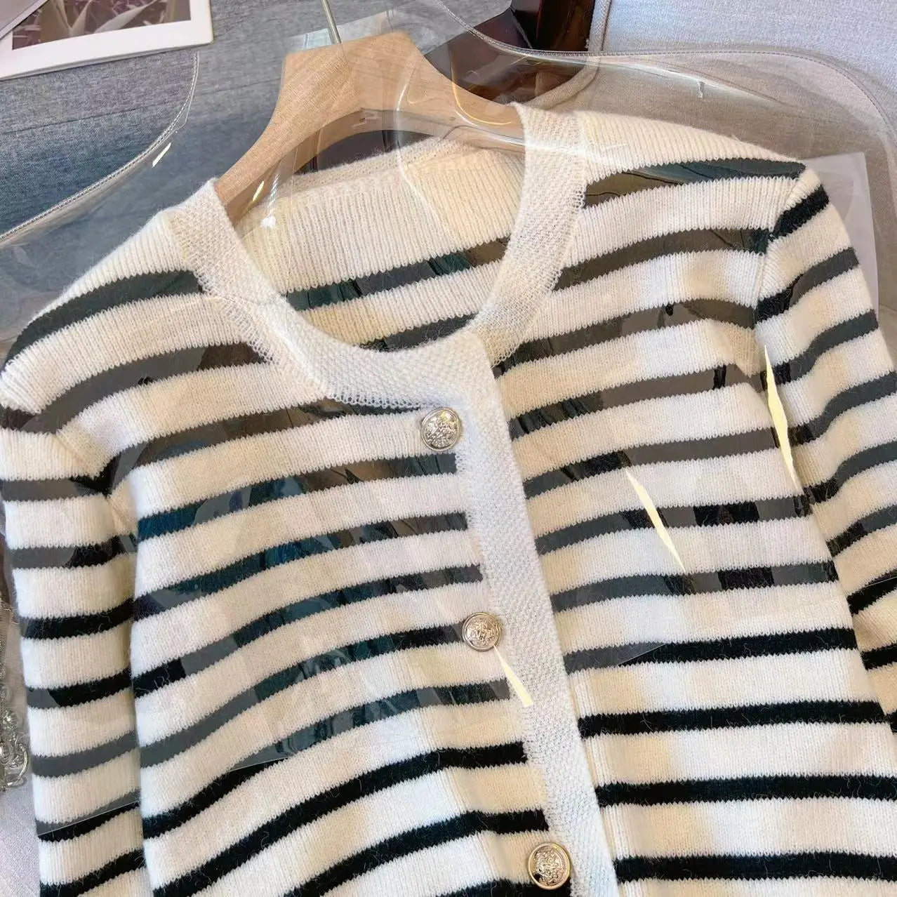 Striped cardigan with buttons on a hanger against a clear background