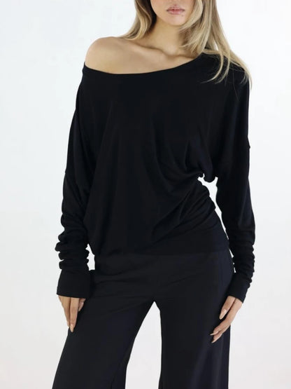 Woman wearing a black off-shoulder top and black pants on a white background