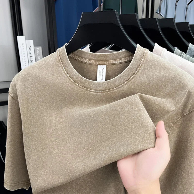 Beige t-shirt held by a hand with a blurred store background
