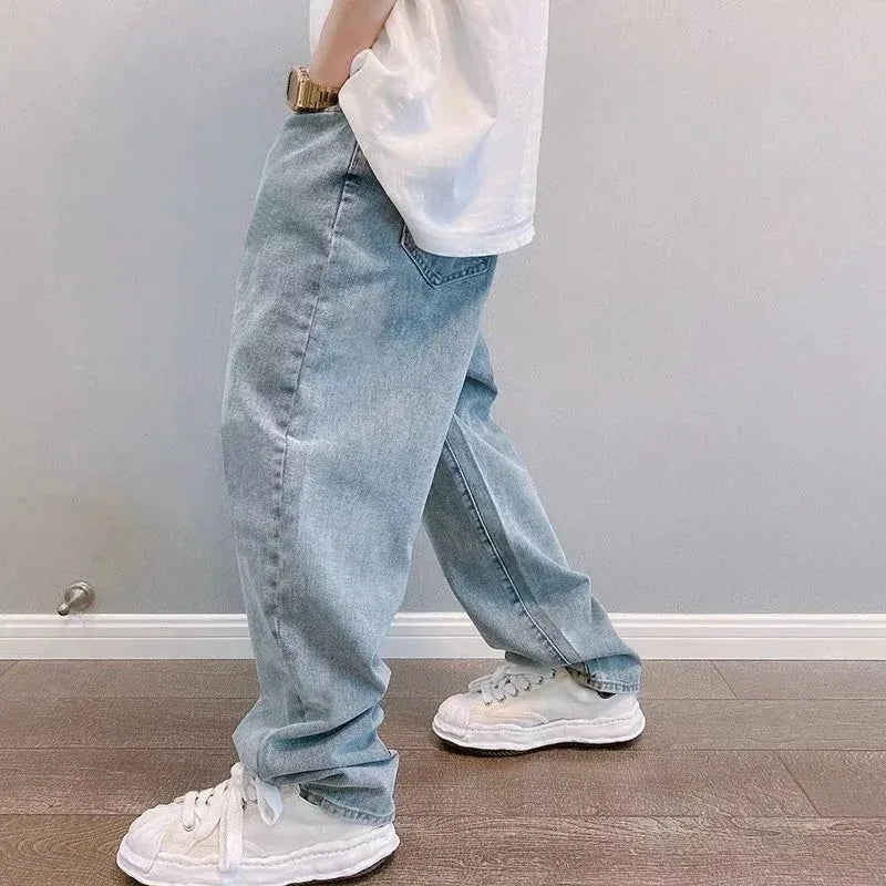 Person wearing light blue jeans and white sneakers in a minimal indoor setting