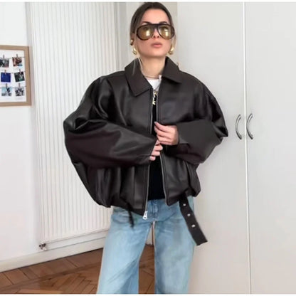 Person wearing a black leather jacket and sunglasses indoors.