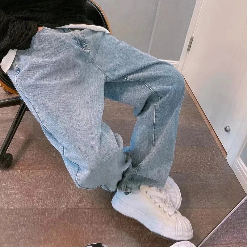 Person wearing light blue jeans and white sneakers sitting on a chair.