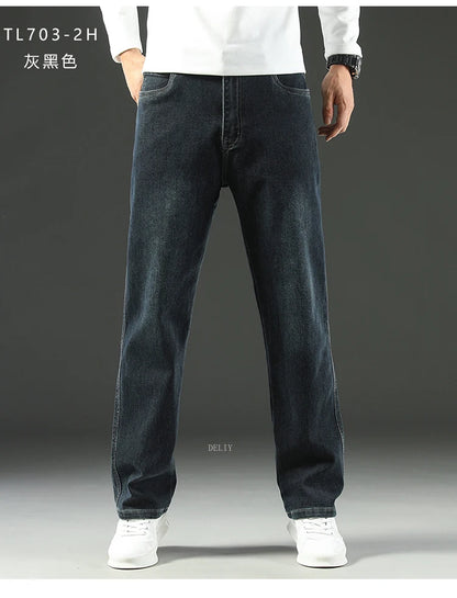 Person wearing dark blue jeans and white shoes on a gray background