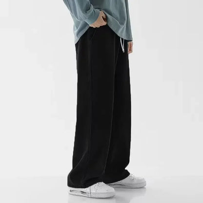 Person wearing black wide-leg pants and a light blue top on a white background