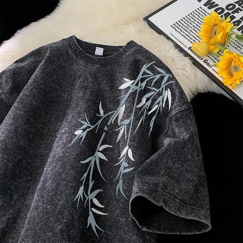 Gray sweatshirt with leaf design on a textured surface with flowers and text.