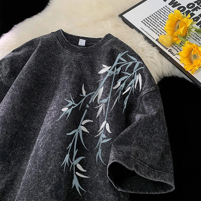 Gray sweatshirt with leaf design on a textured surface with flowers and text.