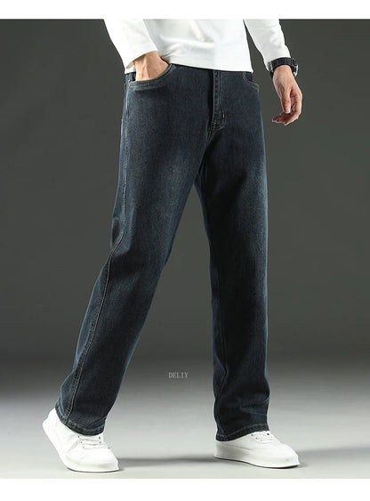Person wearing dark blue jeans and white shoes on a gray background
