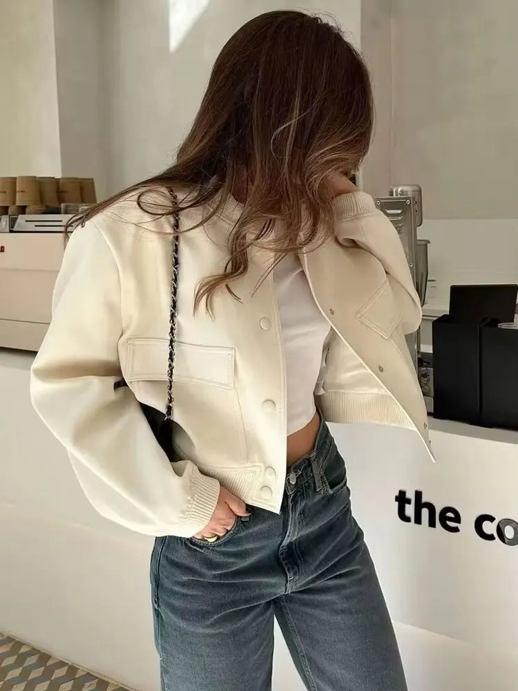 Person wearing a beige jacket and blue jeans in an indoor setting